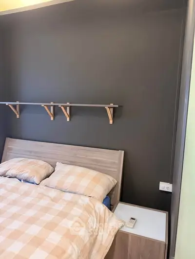 Cozy bedroom with modern design featuring a stylish bed and wall-mounted shelves, perfect for urban living.