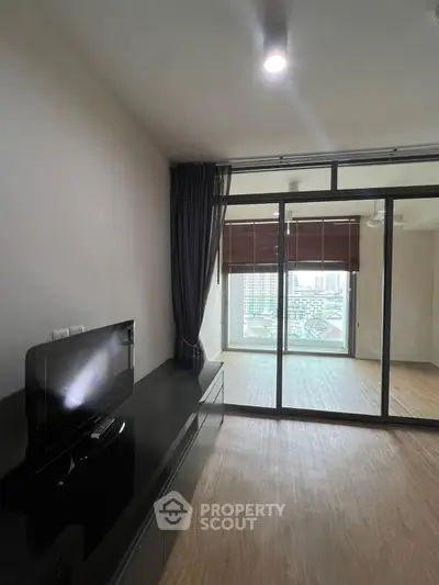 Modern living room with sleek TV unit and large window offering city view