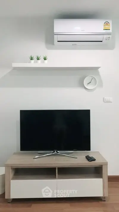 Modern living room with sleek TV setup and air conditioning unit.