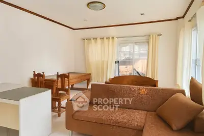 Cozy living room with brown sofa and wooden dining set, bright natural light