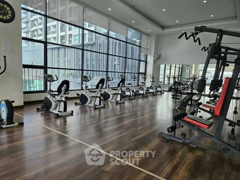 Spacious modern gym with large windows and state-of-the-art equipment in a luxury building.