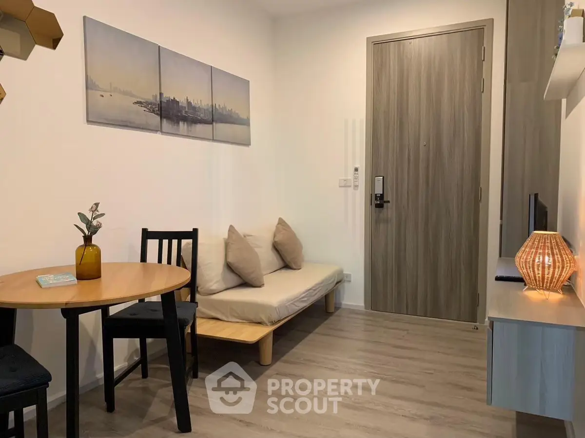 Cozy living room with modern decor and wooden flooring, featuring a small dining area and stylish lighting.