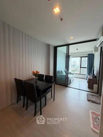 Modern open-plan living and dining area with city view, featuring sleek furniture and stylish decor.