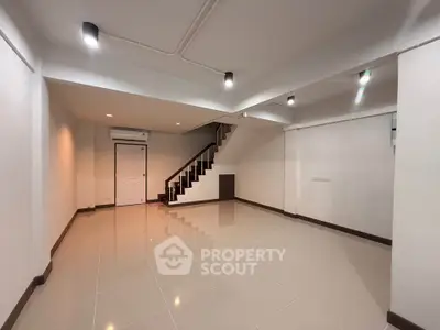 Spacious modern interior with sleek staircase and polished tile flooring, perfect for versatile living space.