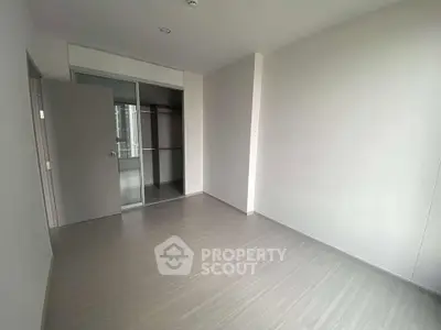 Spacious empty bedroom with sleek flooring and built-in closet in modern apartment.