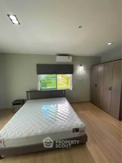 Spacious bedroom with modern design, featuring a large window and ample storage space.