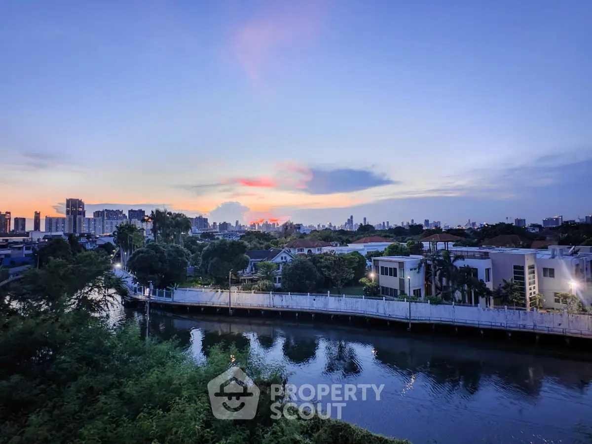 Stunning cityscape view with serene river and lush greenery at sunset, perfect for tranquil urban living.