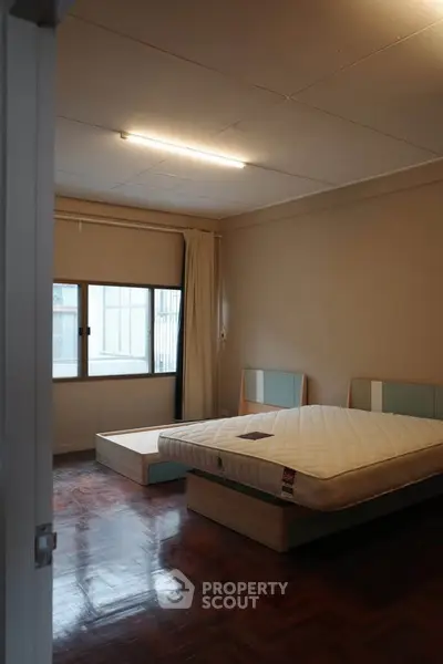 Spacious bedroom with large window and modern bed frame, perfect for comfort and relaxation.