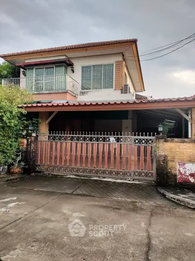 Charming two-story house with gated entrance and spacious driveway, perfect for family living.
