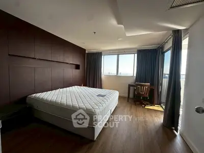 Spacious bedroom with large window and wooden flooring, featuring a comfortable bed and study area.