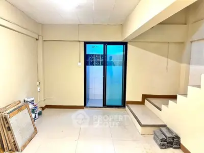 Spacious basement area with tiled flooring and sliding glass door, ideal for storage or renovation.