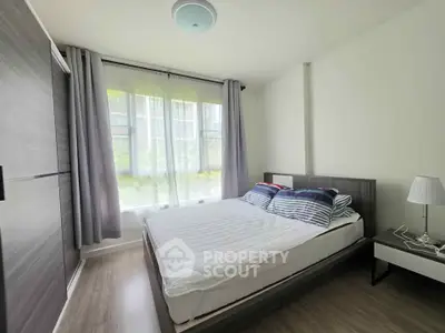 Modern bedroom with large window and stylish furnishings in a bright apartment.