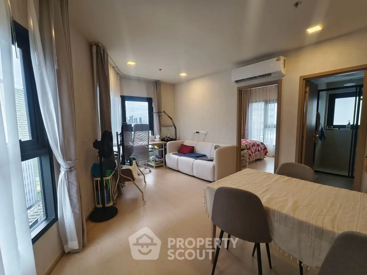 Spacious modern living room with dining area and city view, featuring stylish furniture and natural light.
