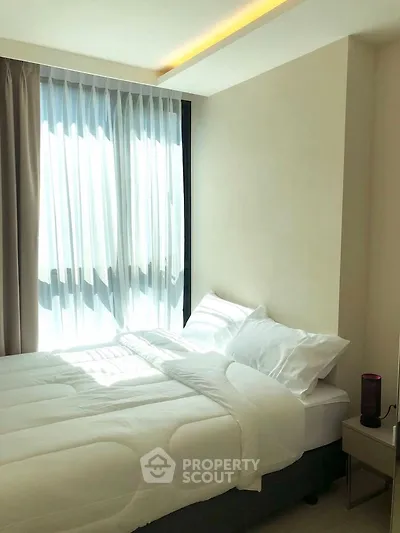 Bright and cozy bedroom with large window and modern decor, perfect for relaxation.