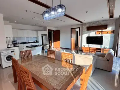Spacious open-plan living room with modern kitchen and elegant dining area, featuring natural light and stylish decor.