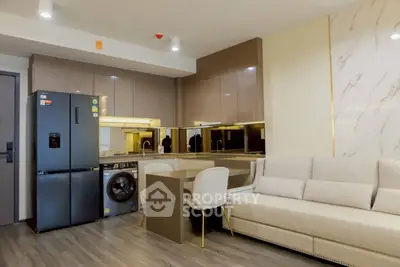 Modern kitchen with sleek appliances and cozy living area in open layout design.