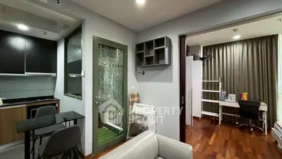 Modern apartment interior with open kitchen and study area, featuring sleek design and wooden flooring.