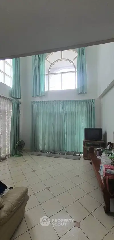 Spacious living room with high ceilings and large windows, perfect for natural light.