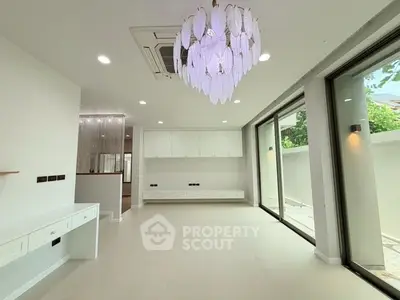 Spacious modern living room with elegant chandelier and large windows for natural light.