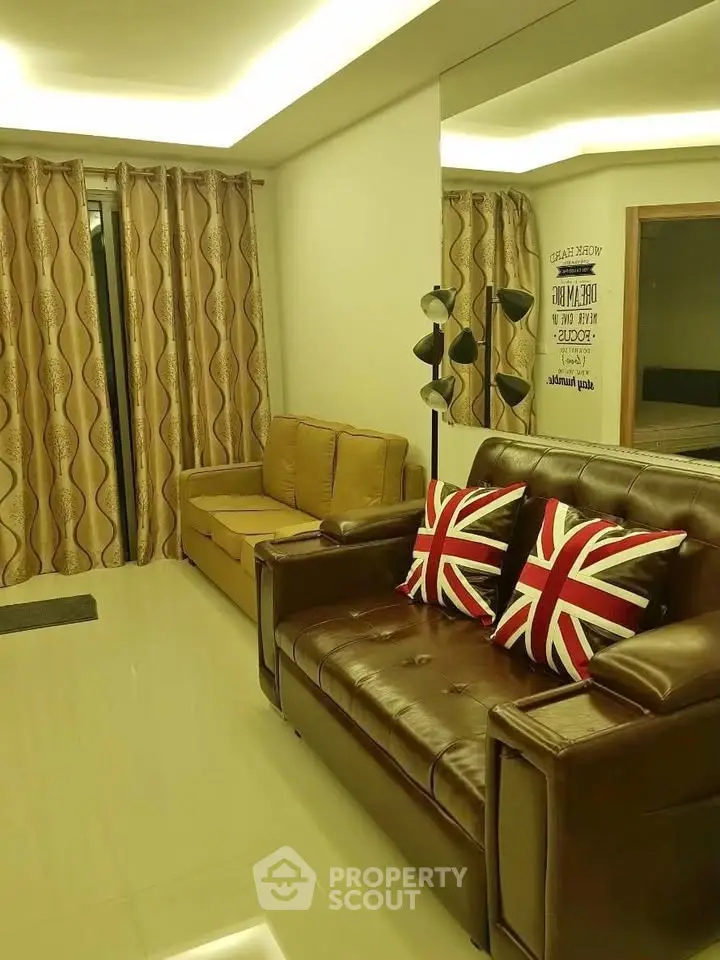 Stylish living room with leather sofas and modern lighting, featuring Union Jack pillows for a chic touch.