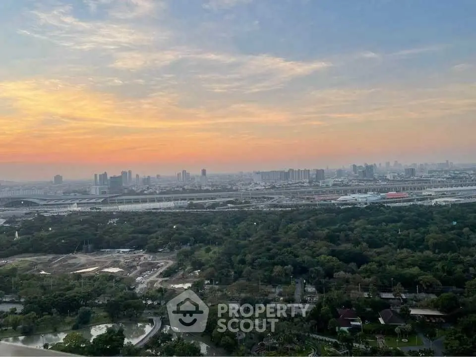 Stunning cityscape view with lush greenery and vibrant sunset sky, perfect for urban living enthusiasts.