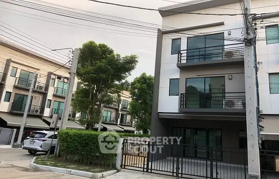 Modern townhouse exterior with balconies and gated entrance in suburban neighborhood.