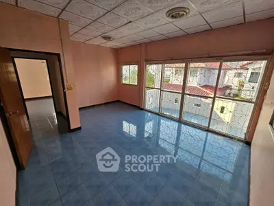 Spacious living room with large windows and blue tiled floor, offering ample natural light.