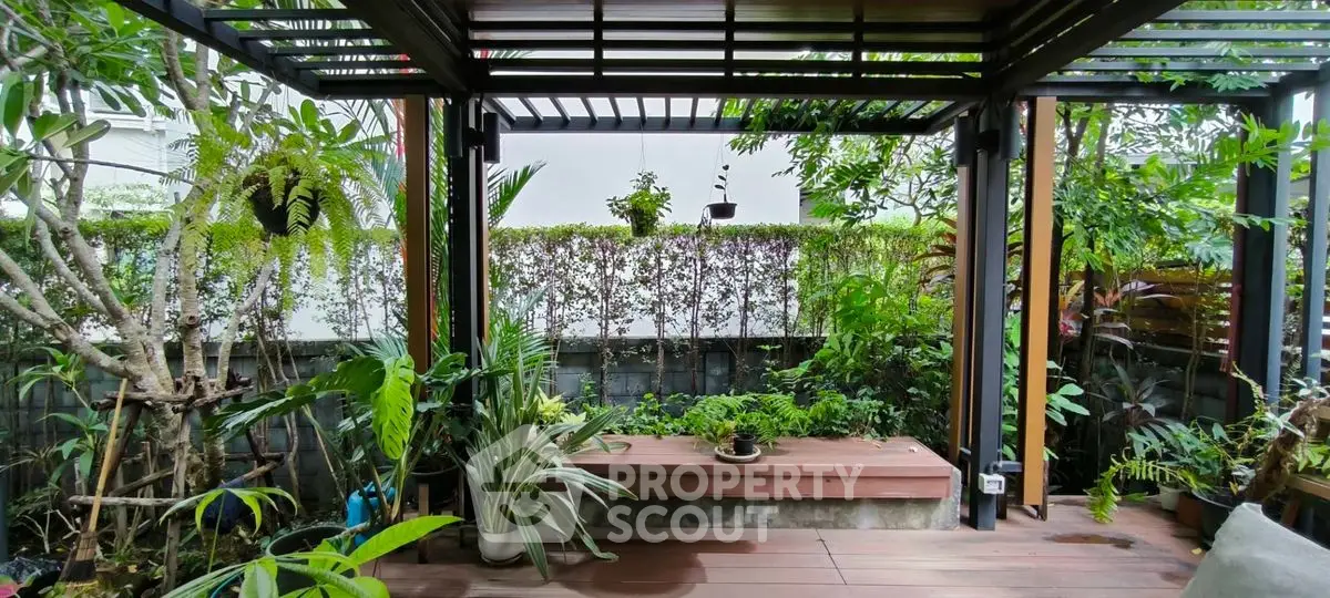 Charming garden patio with lush greenery and modern pergola, perfect for outdoor relaxation.