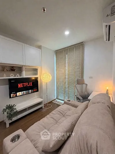 Cozy living room with modern decor, featuring a plush sofa, wall-mounted TV, and stylish lighting.