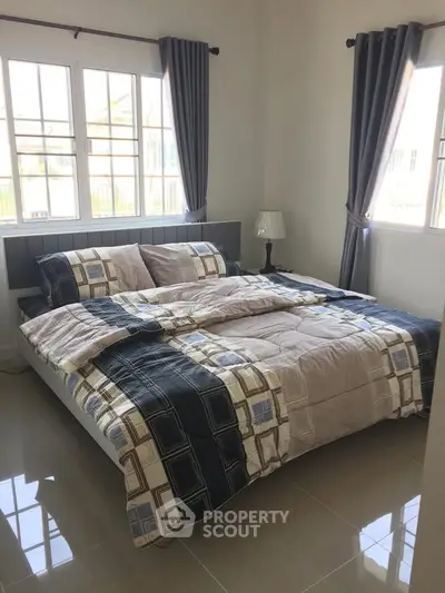 Cozy bedroom with large windows and stylish bedding in a modern home.