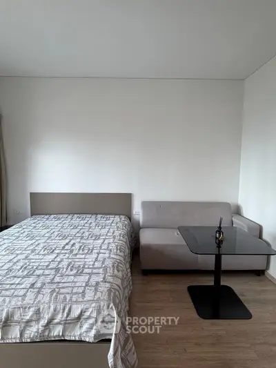 Modern bedroom with cozy bed and stylish sofa in minimalist design.