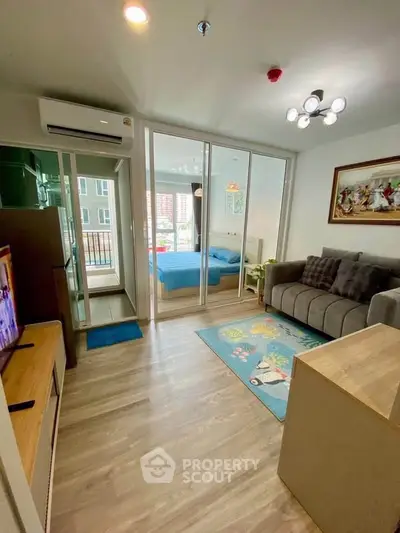 Modern living room with glass doors leading to a cozy bedroom, featuring stylish decor and natural light.