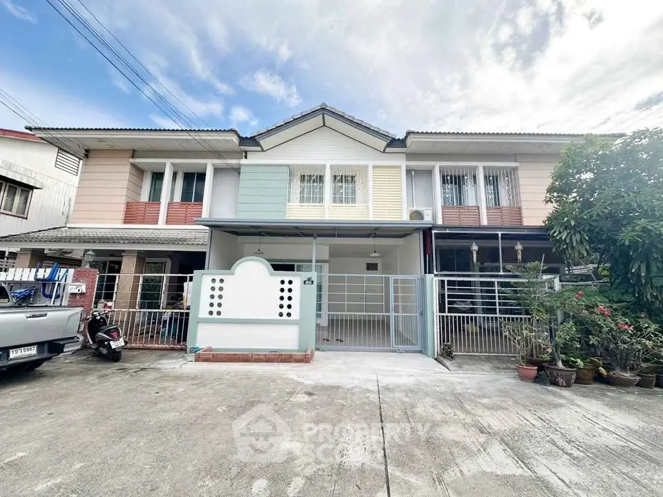 Charming two-story townhouse with gated entrance and lush greenery in a serene neighborhood.