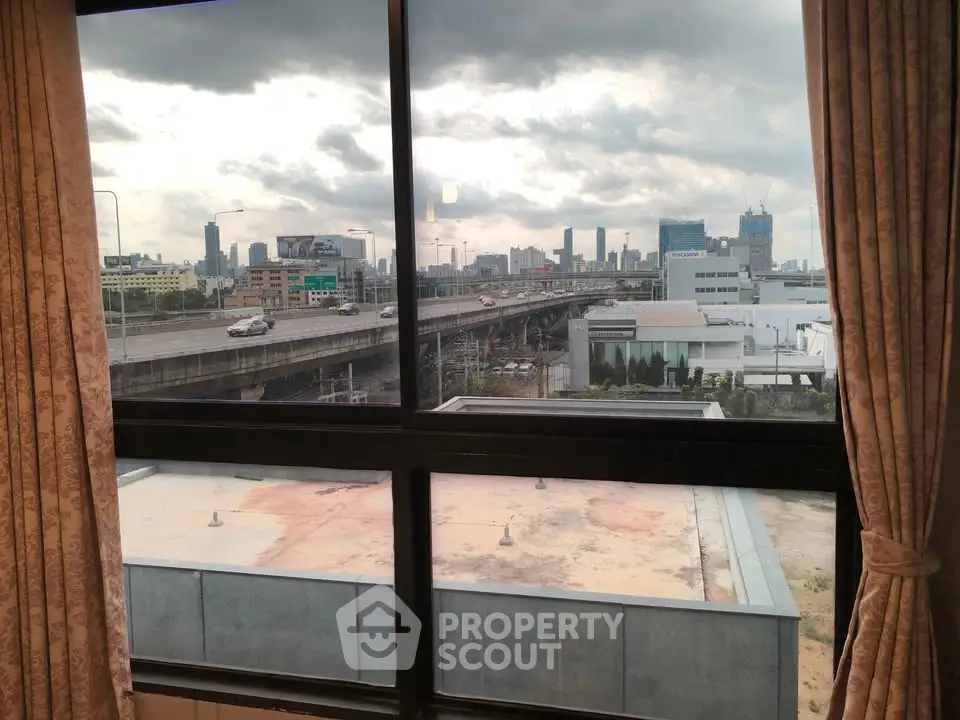 Stunning cityscape view from a high-rise apartment window, showcasing urban skyline and highway.