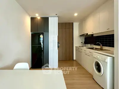 Modern kitchen with sleek appliances and washing machine in open layout.