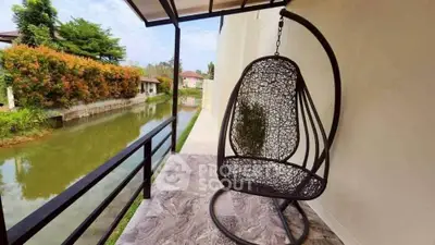 Charming balcony with hanging chair overlooking serene canal view.