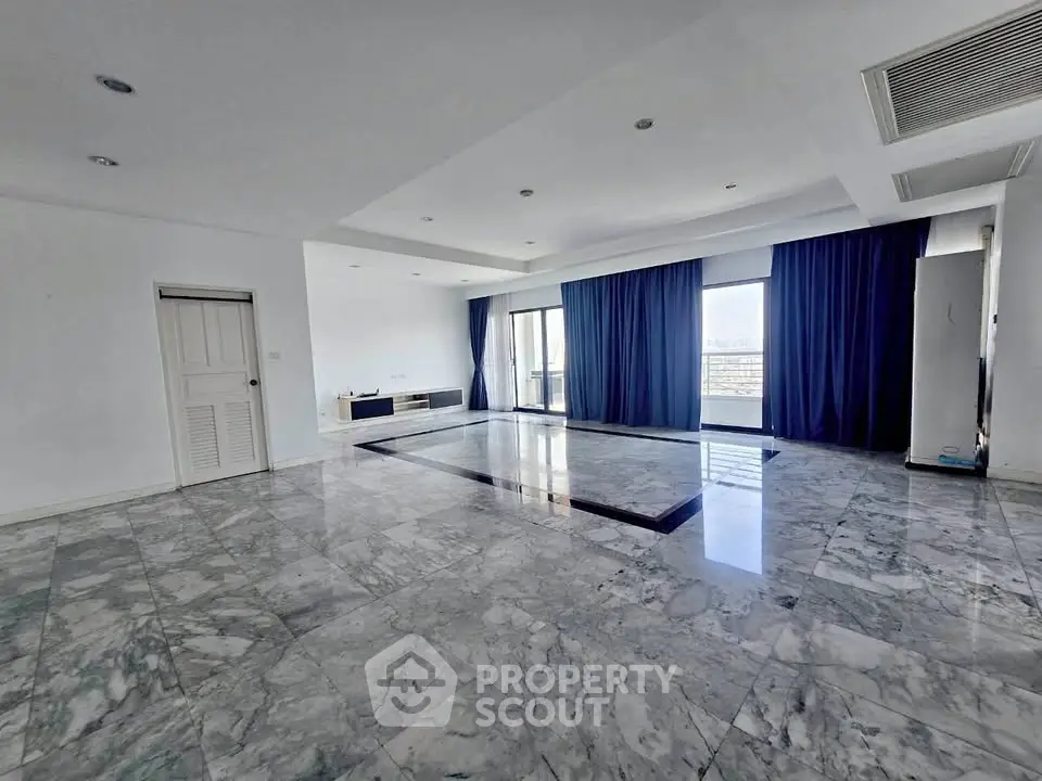 Spacious marble-floored living room with large windows and balcony access.