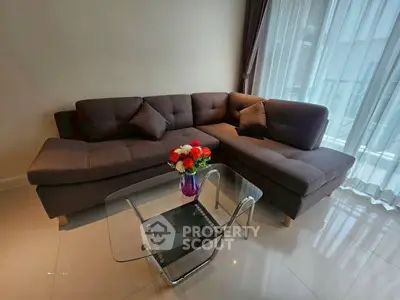 Modern living room with stylish sectional sofa and glass coffee table, featuring elegant decor and natural light.