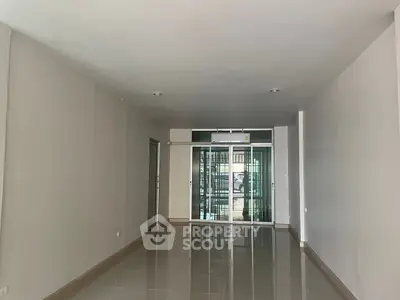 Spacious empty room with glossy tiled floor and large glass doors