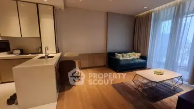 Modern living room with open kitchen, featuring sleek design and natural light.