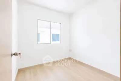Bright empty room with wooden flooring and a window, perfect for customization.