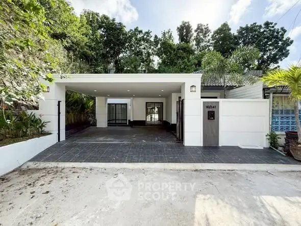 Charming single-story home with spacious driveway and lush greenery, perfect for serene living.