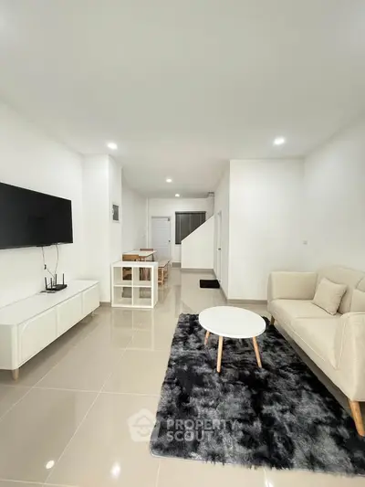 Modern living room with sleek furniture and open layout, featuring a cozy sofa and stylish decor.