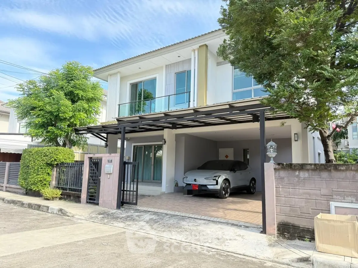 Modern two-story house with carport and lush greenery in a serene neighborhood.