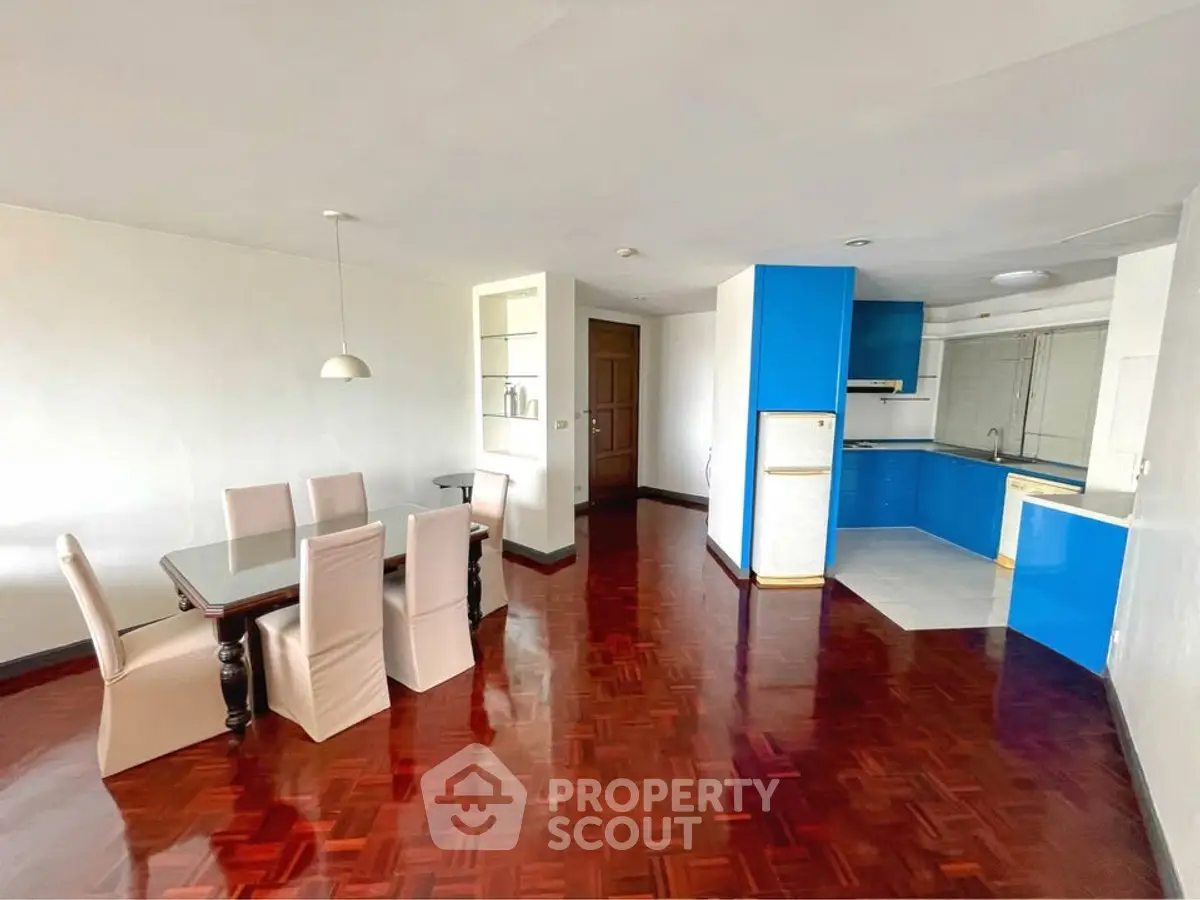 Spacious open-plan living and dining area with modern kitchen and elegant wooden flooring.