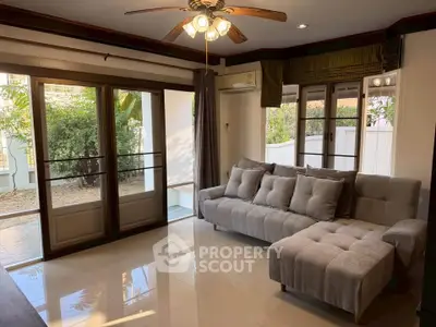 Spacious living room with plush gray sofa and large windows overlooking garden