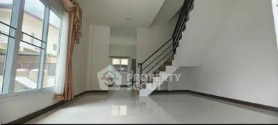 Spacious modern living room with large windows and elegant staircase
