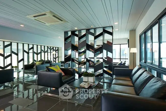 Modern living room with stylish mirrored wall and sleek black sofas.