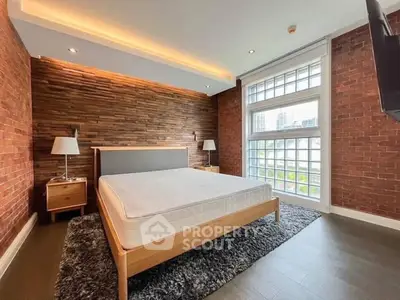 Stylish bedroom with brick walls and large window offering city views
