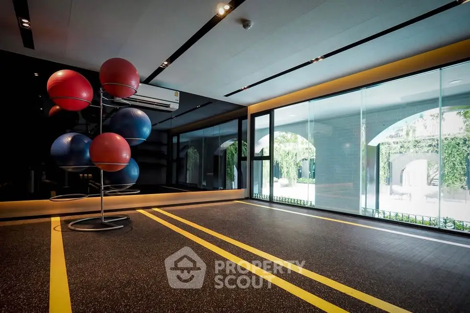 Modern gym with exercise balls and large windows overlooking greenery
